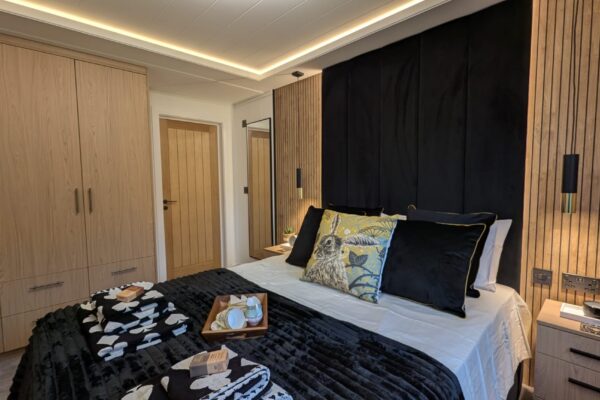 Main bedroom with velvet headboard in luxury lodge for sale in North Wales | Maes Mynan Park | YourRetreats