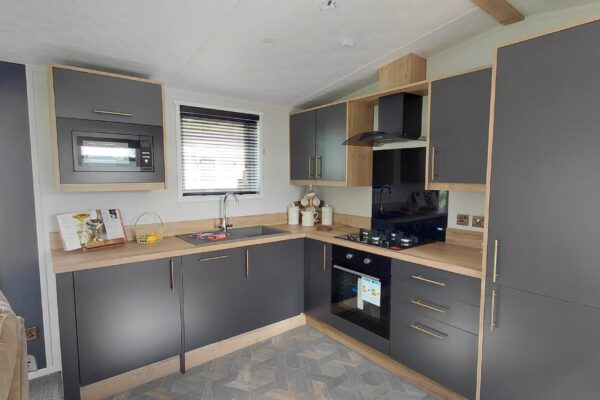 U-shaped kitchen with dark gray cabinets, light wood countertops, and a built-in microwave above the counter.
